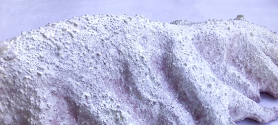 Detail of the side of an abstract paper mache sculpture by MJ Seal that resembles a cross between a mountain and some primitive clawed sea creature